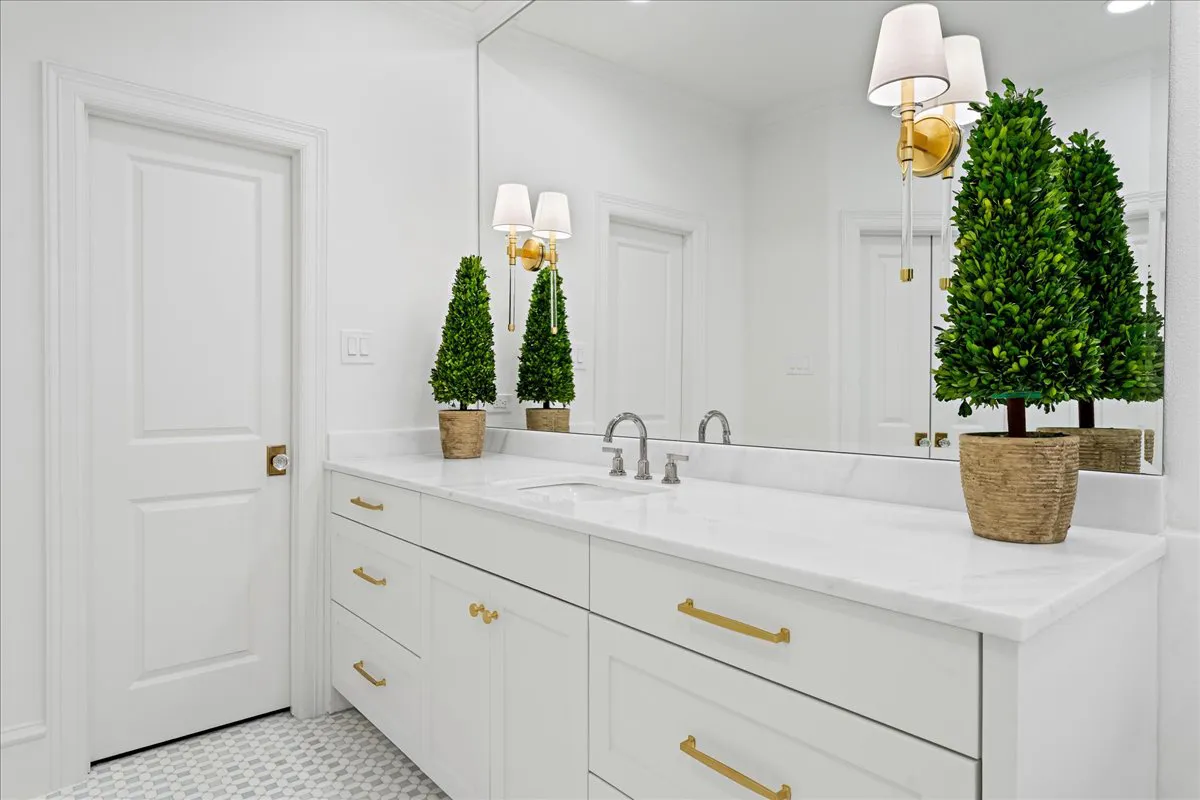 Pegasus marble vanity counters on white cabinetry with brass hardware and a widespread faucet, installed by Dallas Countertop
