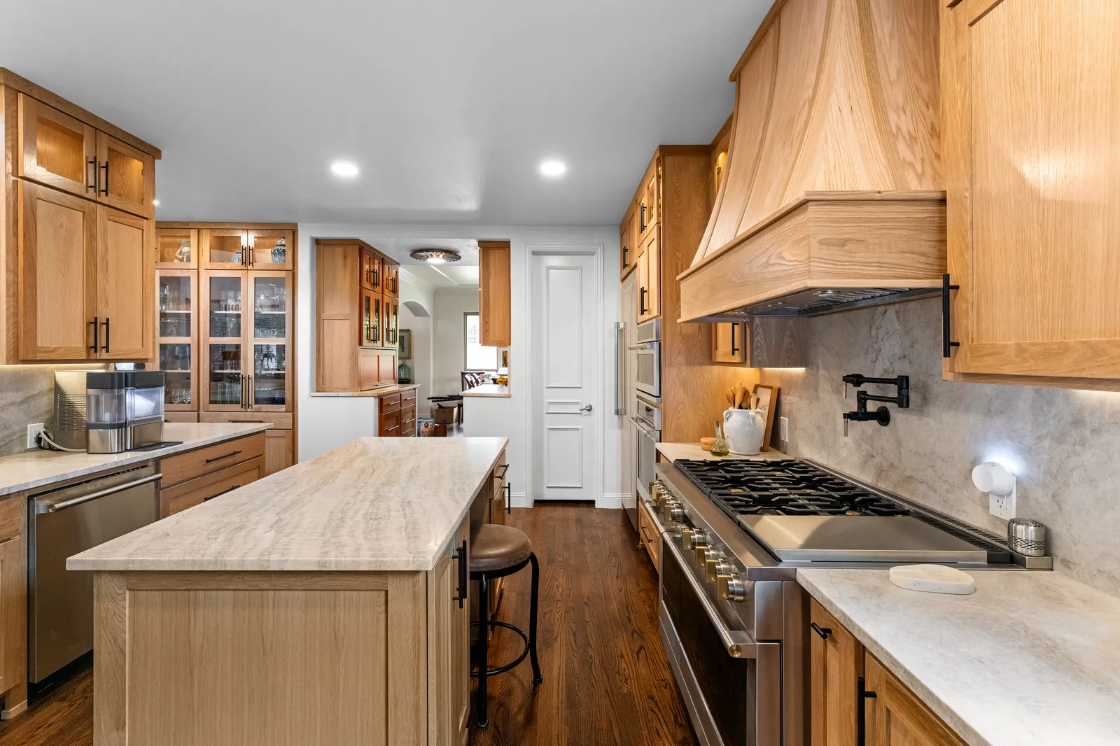 Quartzite island with seating and a matching quartzite backsplash at the range in a Plano, TX kitchen