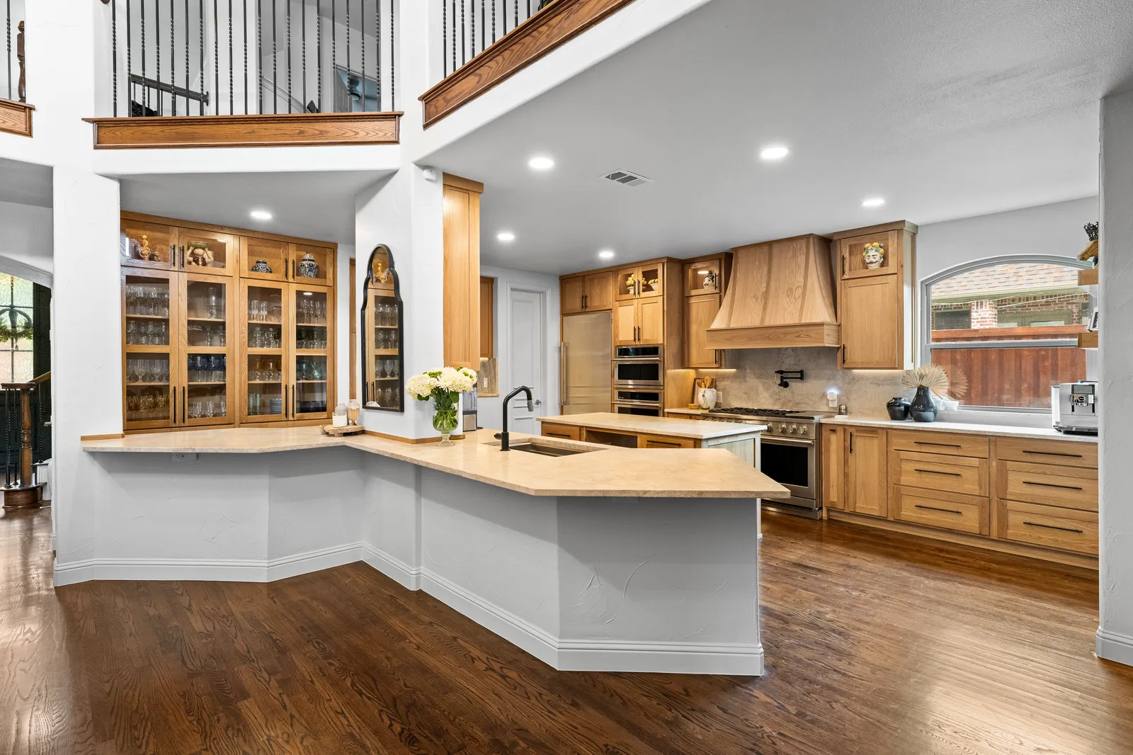 Wide view of a Plano, TX kitchen with Taj Mahal quartzite island and perimeter counters and white oak cabinetry
