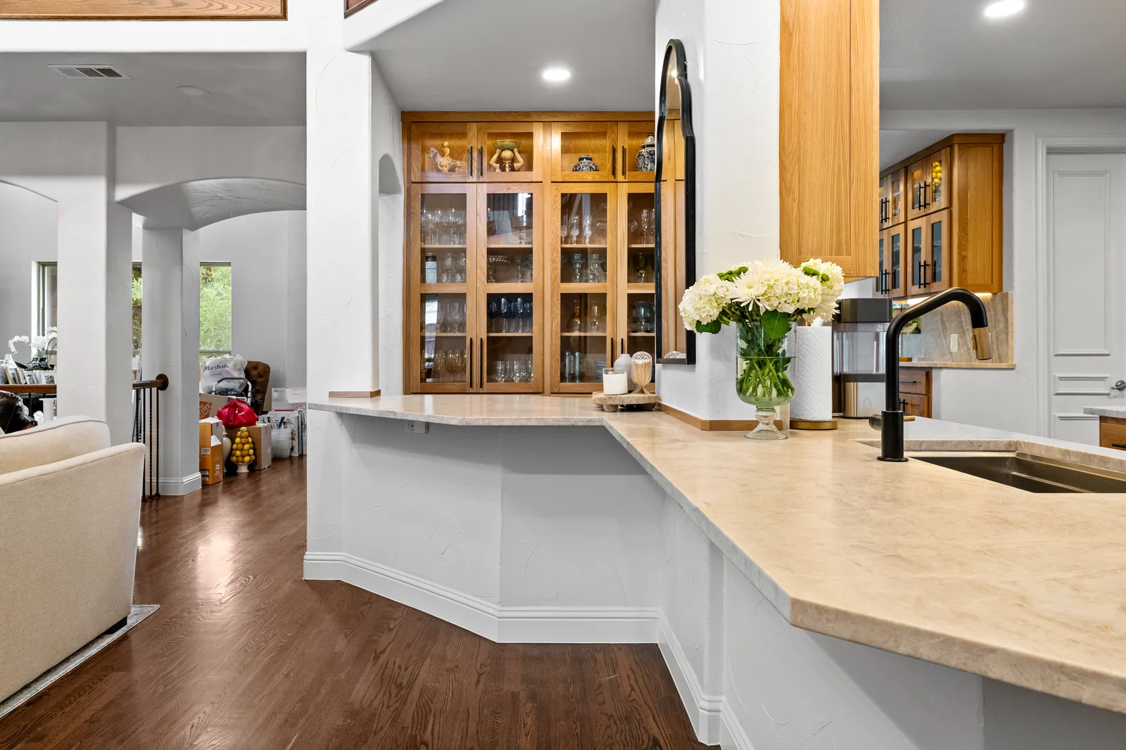 Quartzite peninsula counter with a black faucet opening to the living room in Plano, TX