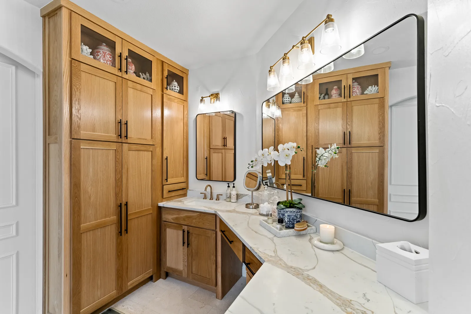 Primary bathroom with a quartzite-topped white oak vanity, tall cabinet, and black-framed mirrors in Plano, TX