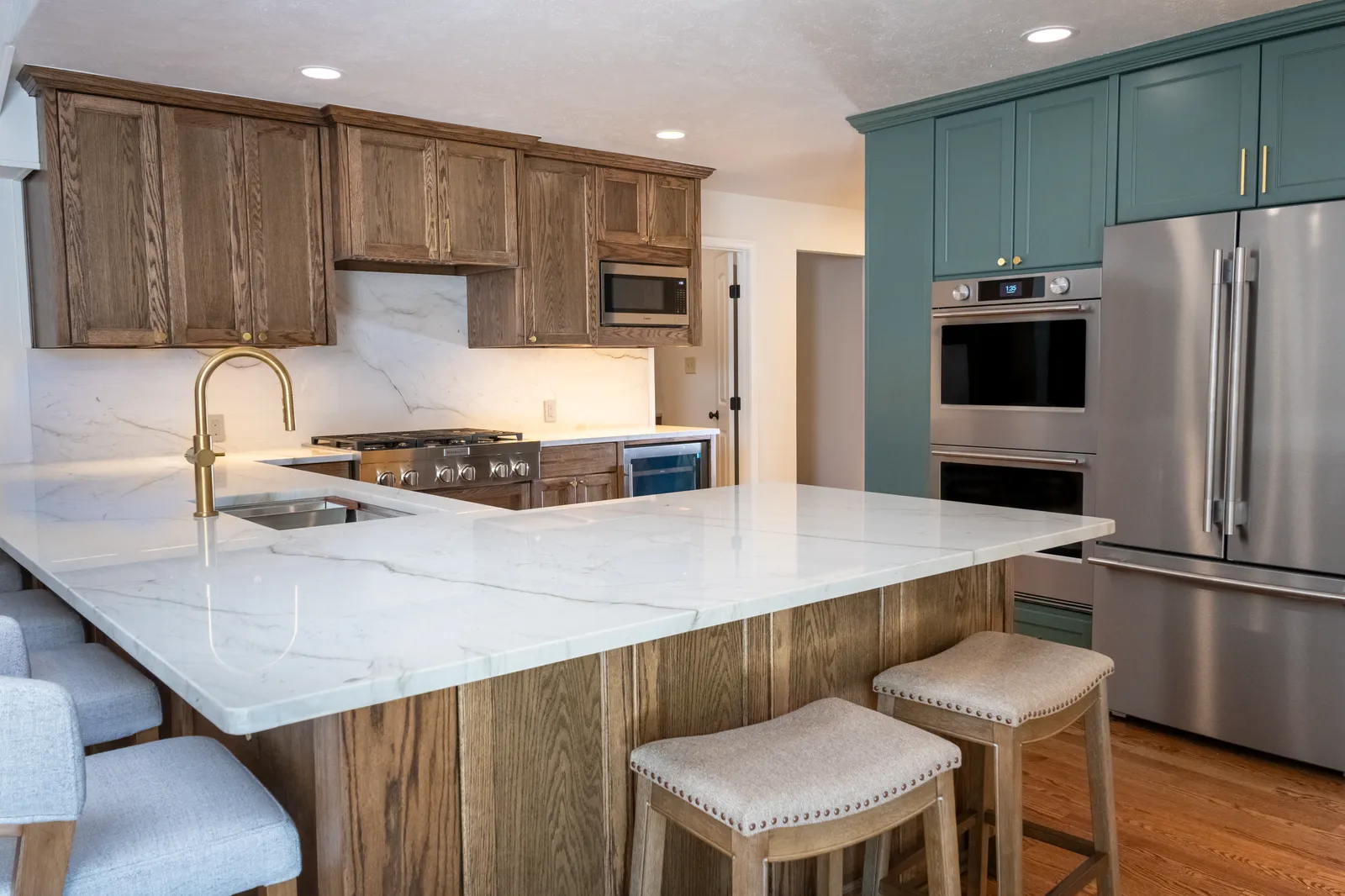 Preston Hollow, Dallas kitchen with quartzite counters, stained oak cabinets, and a brass faucet